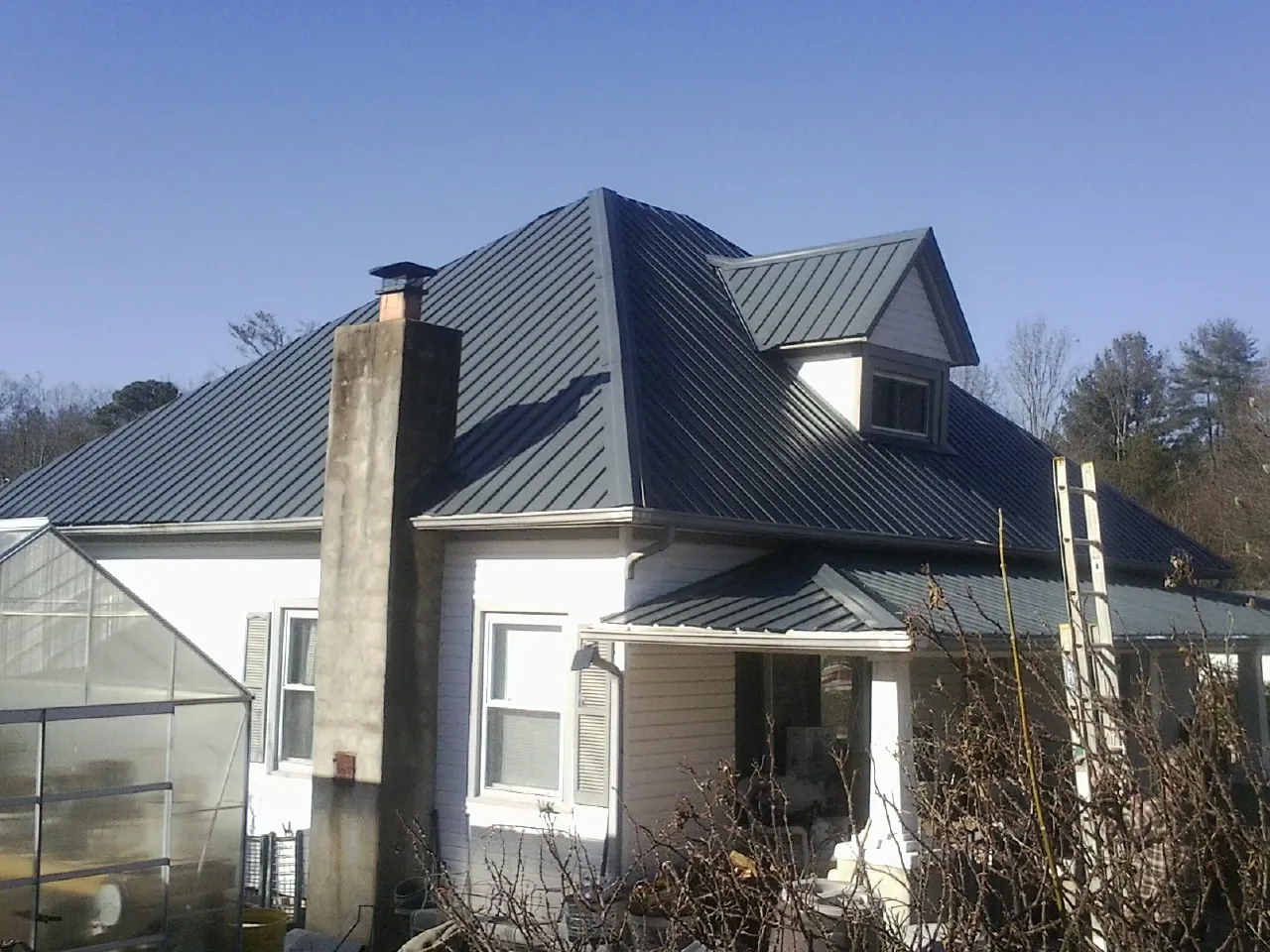 Dark blue standing seam metal roof on a white farmhouse with dormer — Slate & Tile Roof Repair by Roofing Brothers in Ewing