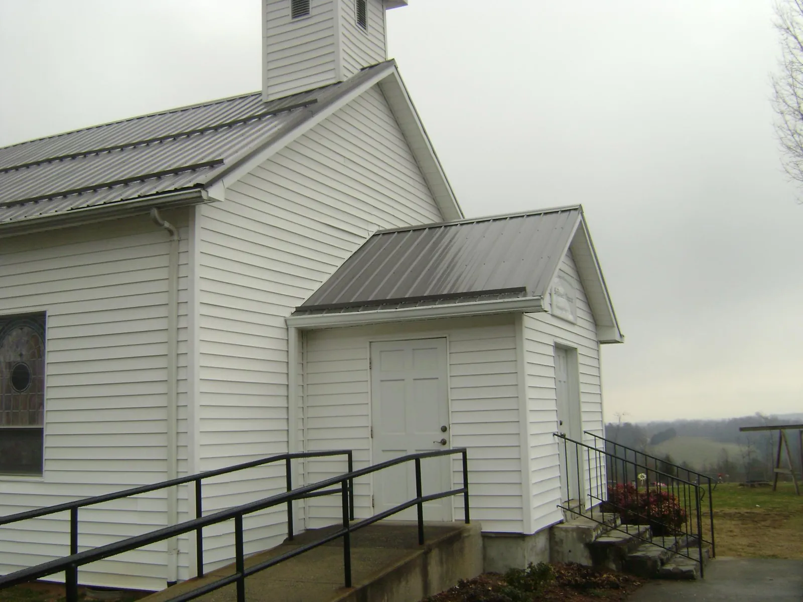 Gray metal roof on a white clapboard church with a steeple in Ewing
