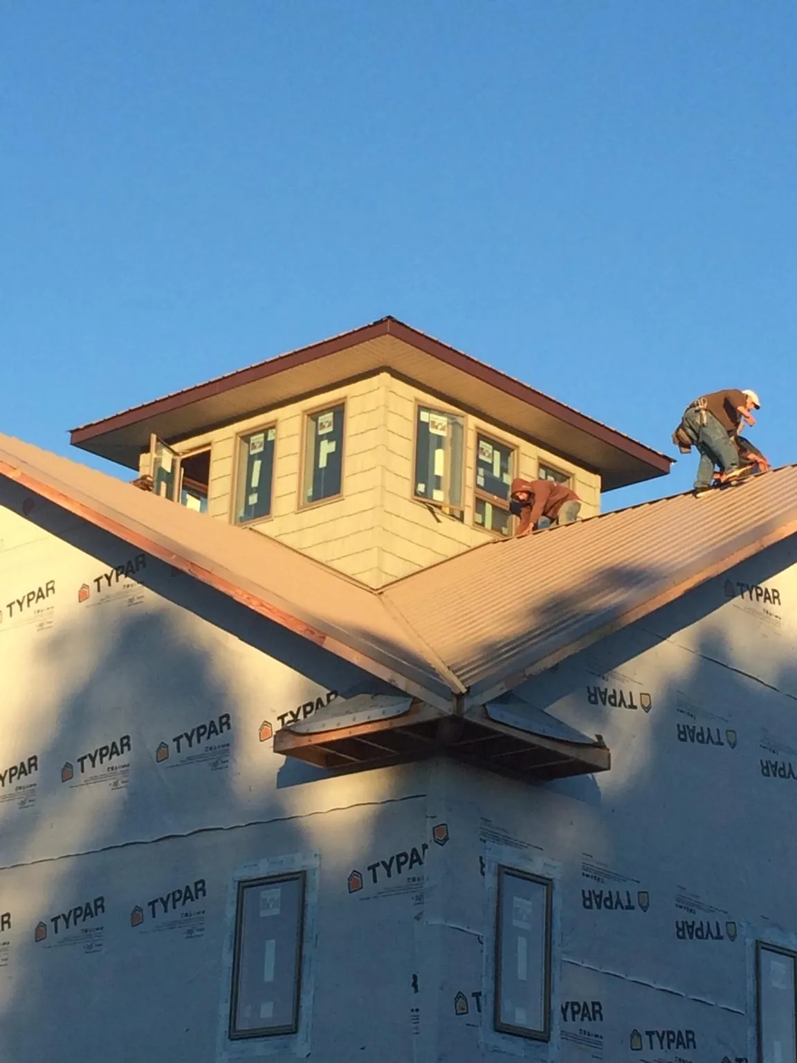 Roofers working around a rooftop cupola on a new metal roof at sunset — Roof Waterproofing in Ewing by Roofing Brothers